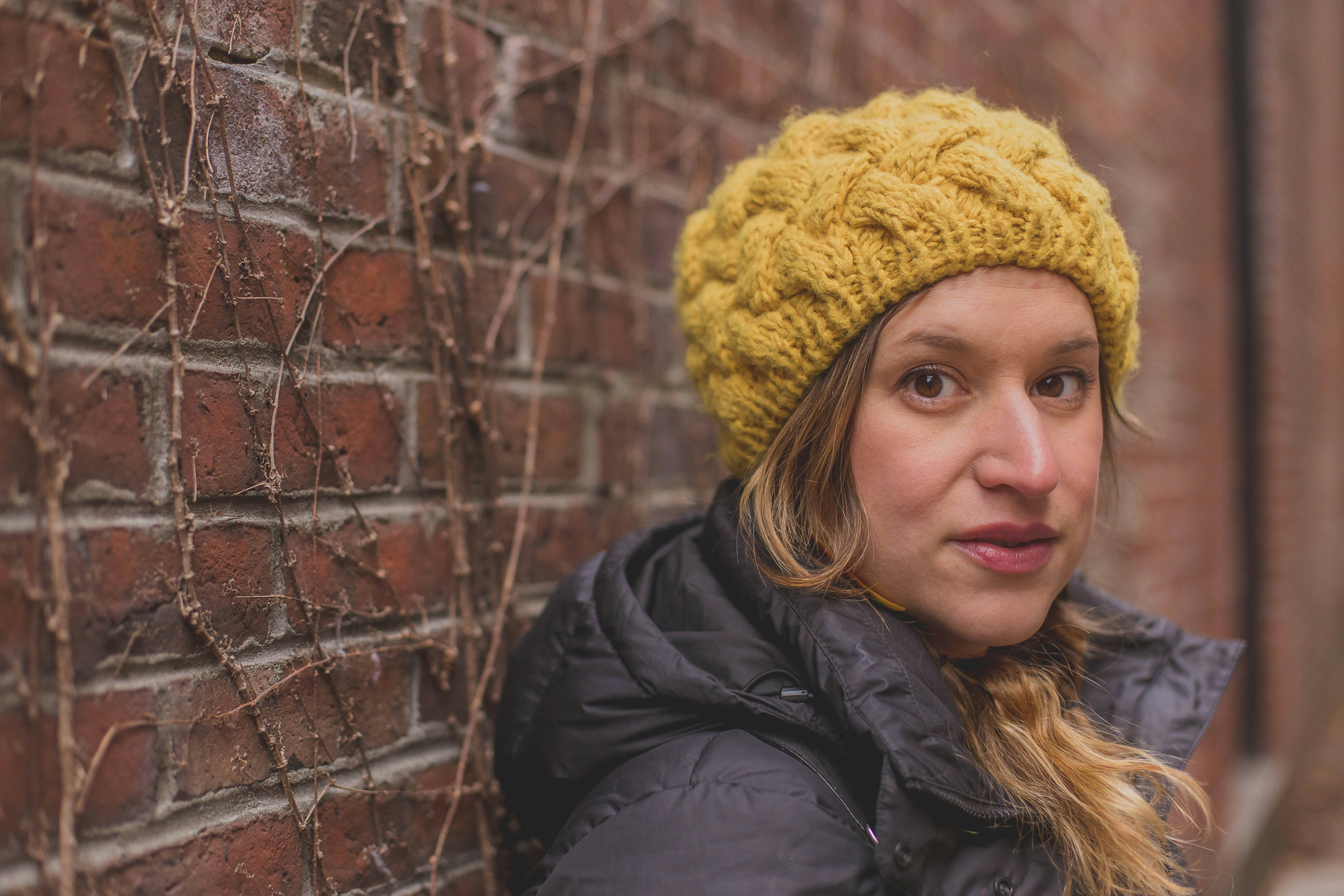 woman in black jacket wearing yellow knit cap